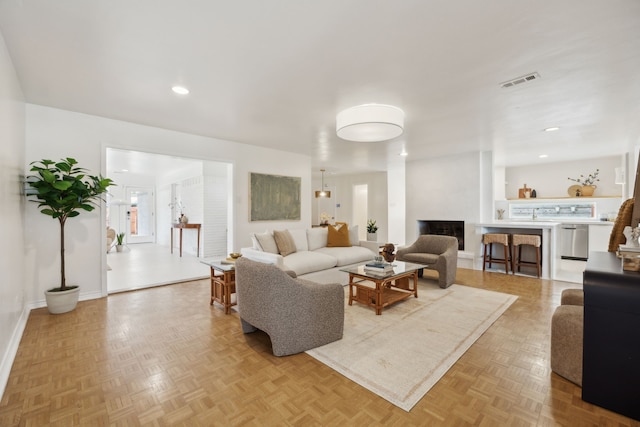 living area featuring recessed lighting, visible vents, a fireplace with raised hearth, and baseboards