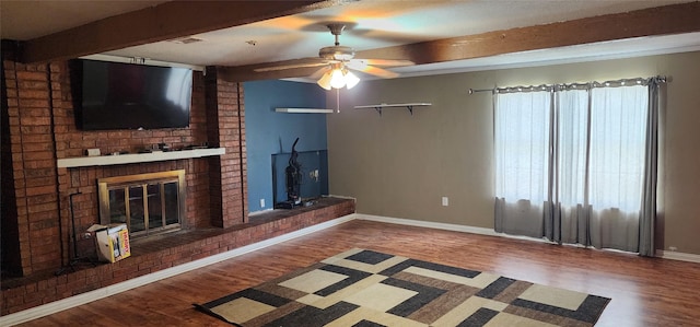 unfurnished living room featuring beamed ceiling, baseboards, wood finished floors, and a fireplace