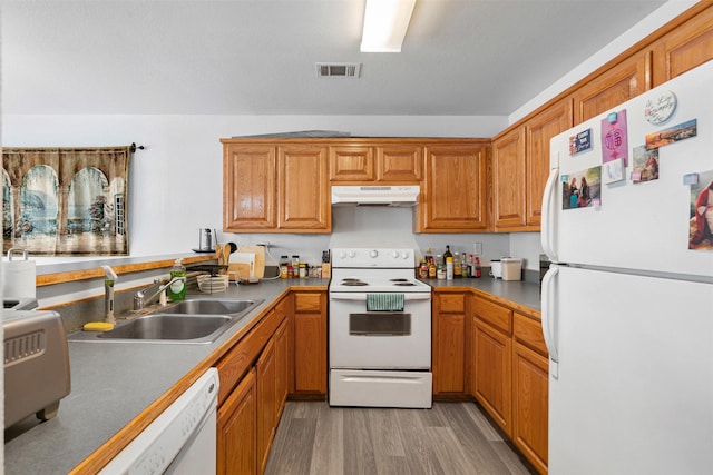 kitchen with visible vents, light wood-style flooring, a sink, under cabinet range hood, and white appliances