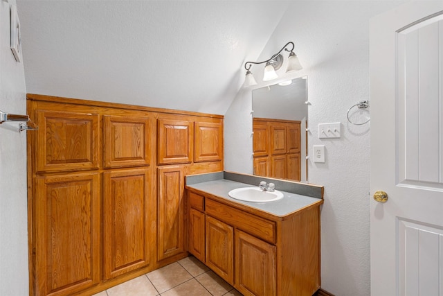 bathroom with tile patterned floors, a textured wall, vanity, and vaulted ceiling