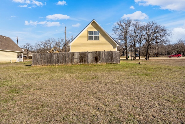 view of side of home featuring a yard and fence