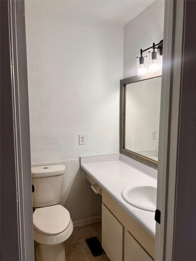 bathroom featuring tile patterned floors, toilet, vanity, and a textured wall