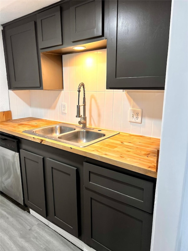 kitchen featuring gray cabinetry, a sink, backsplash, wooden counters, and dishwasher