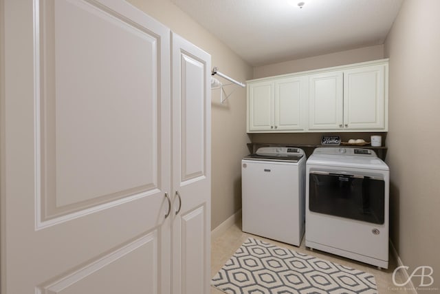 washroom with cabinet space, baseboards, and washing machine and clothes dryer