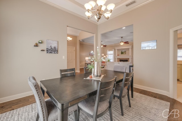 dining room featuring visible vents, a notable chandelier, ornamental molding, wood finished floors, and a fireplace