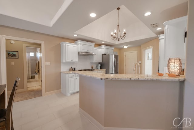 kitchen with visible vents, under cabinet range hood, a peninsula, white cabinets, and stainless steel appliances