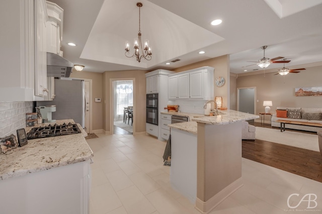 kitchen featuring a sink, open floor plan, white cabinetry, a peninsula, and a raised ceiling