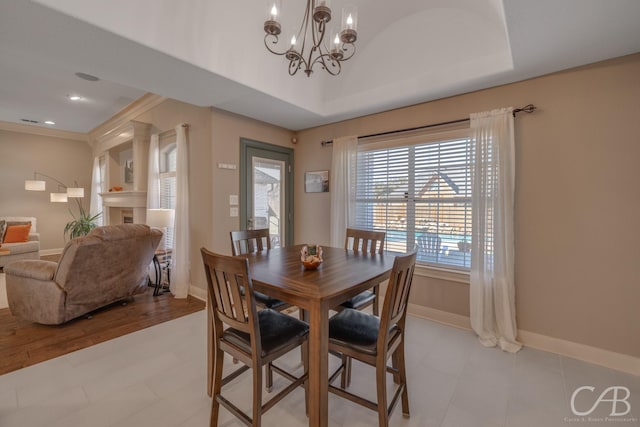 dining space with baseboards, recessed lighting, crown molding, a raised ceiling, and a notable chandelier