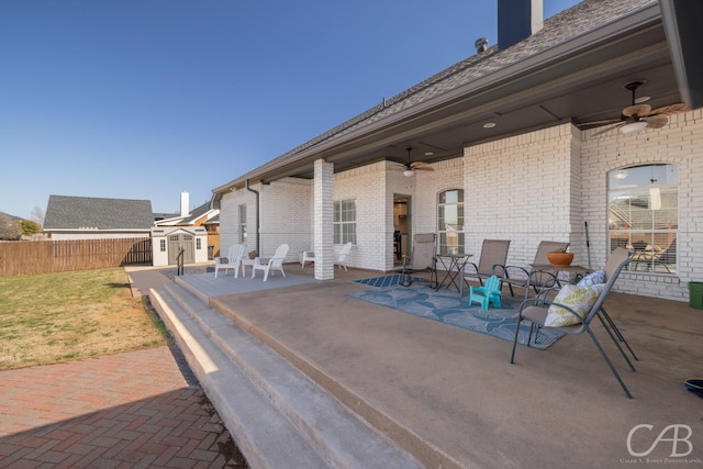 view of patio with fence, an outbuilding, ceiling fan, and a shed