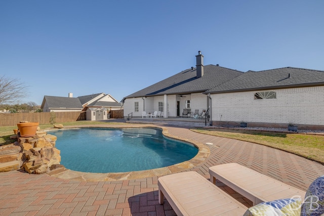 view of swimming pool with an outbuilding, a fenced backyard, a shed, a fenced in pool, and a patio area