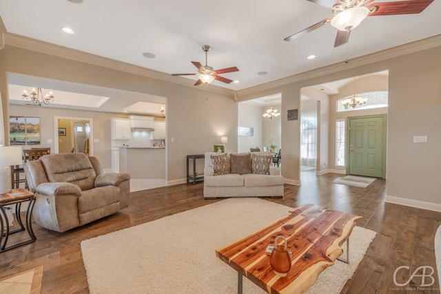 living room with ornamental molding, ceiling fan with notable chandelier, dark wood-style floors, recessed lighting, and baseboards