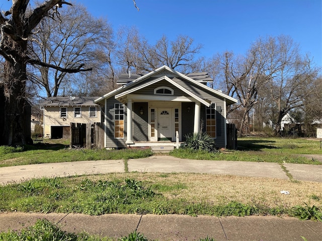 bungalow featuring a front yard, brick siding, and covered porch