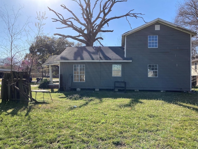 back of property with a lawn and a shingled roof