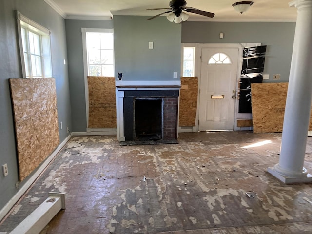 unfurnished living room with decorative columns, a ceiling fan, a fireplace, and crown molding