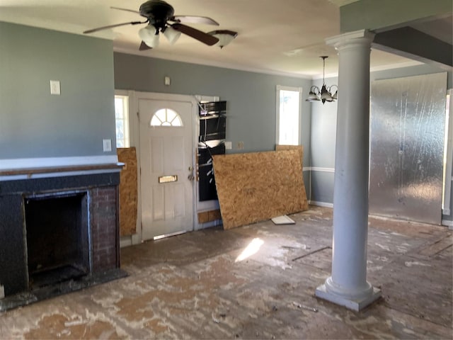 unfurnished living room featuring ceiling fan with notable chandelier, a fireplace, crown molding, and decorative columns