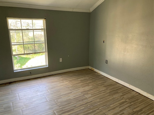 empty room with baseboards, wood finished floors, and crown molding