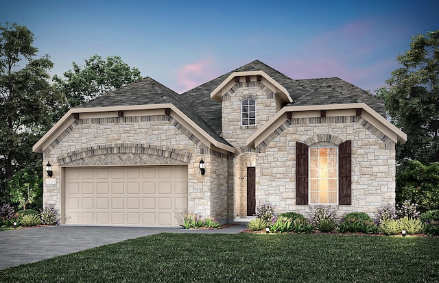 french country inspired facade featuring an attached garage, a lawn, driveway, and roof with shingles