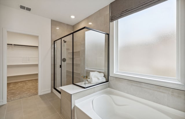 bathroom with visible vents, a shower stall, a spacious closet, a garden tub, and tile patterned floors