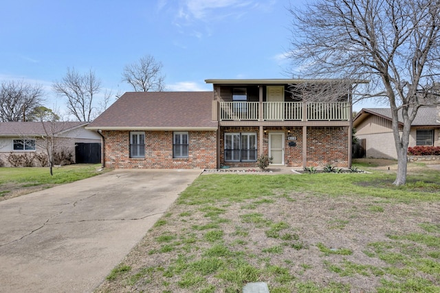 view of front of property featuring brick siding, a balcony, and a front yard