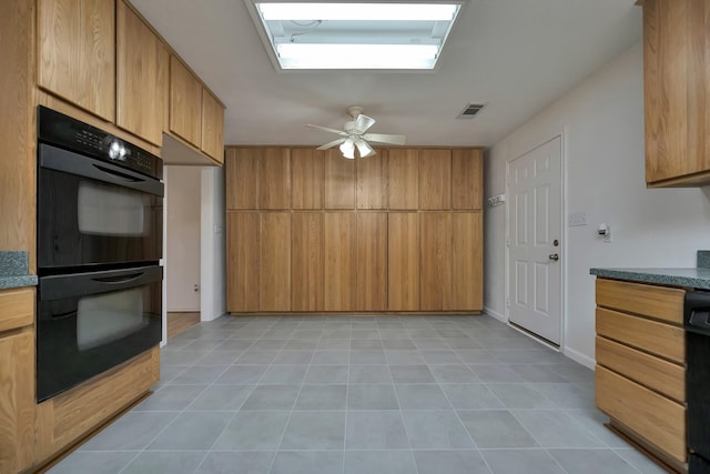 kitchen featuring visible vents, brown cabinets, dobule oven black, light tile patterned floors, and ceiling fan