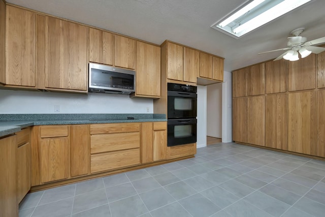 kitchen featuring light tile patterned floors, a ceiling fan, black appliances, dark countertops, and brown cabinets