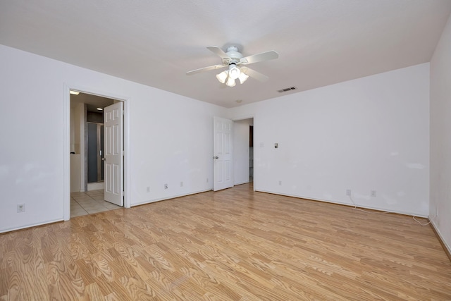 empty room featuring ceiling fan, visible vents, and light wood-type flooring