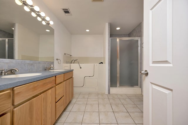 full bathroom featuring visible vents, double vanity, a stall shower, a sink, and tile patterned floors