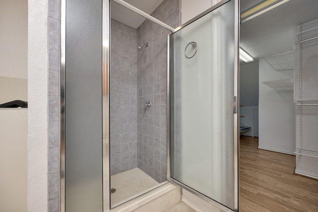 full bathroom featuring a stall shower and wood finished floors