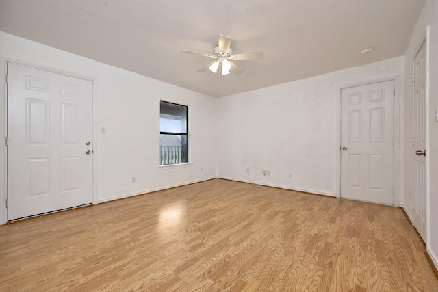 empty room featuring ceiling fan, baseboards, and light wood-style floors