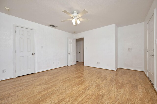 unfurnished room with a ceiling fan, light wood-style floors, visible vents, and baseboards