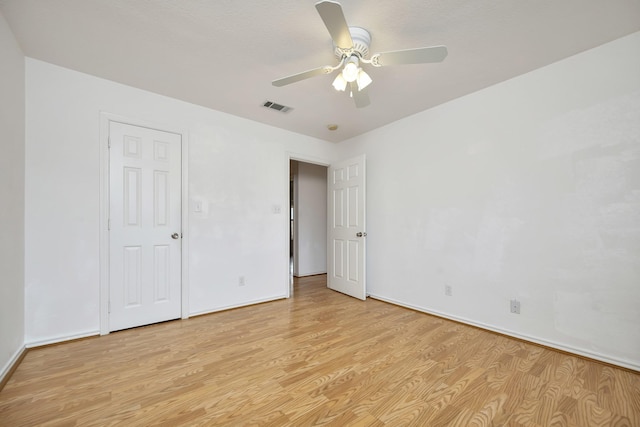 spare room featuring light wood-type flooring, visible vents, baseboards, and ceiling fan