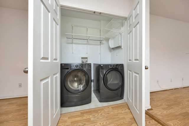 washroom featuring laundry area, wood finished floors, and washing machine and dryer