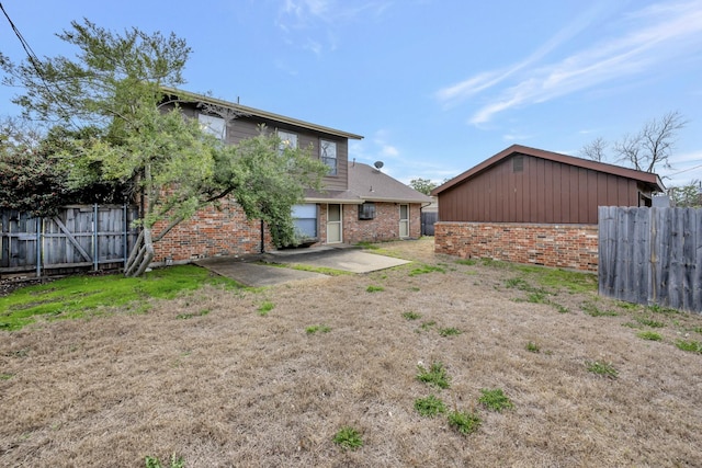 rear view of property featuring a patio, brick siding, and fence