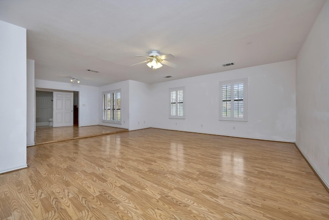 spare room with light wood-type flooring, visible vents, and a ceiling fan