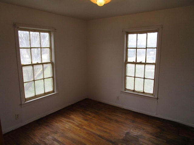 spare room featuring dark wood-style floors and baseboards