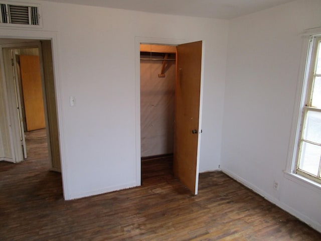 unfurnished bedroom featuring a closet, visible vents, baseboards, and wood finished floors