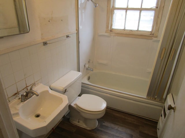 full bath featuring a sink, toilet, tile walls, and shower / bathtub combination