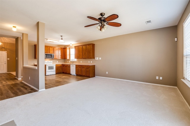 kitchen with visible vents, brown cabinets, white appliances, and carpet