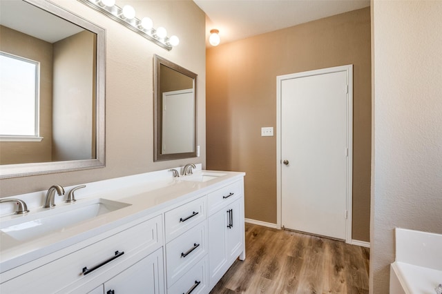 full bath featuring a sink, a bathtub, wood finished floors, and double vanity