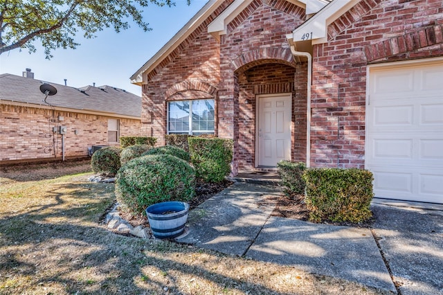 view of exterior entry featuring brick siding and a garage