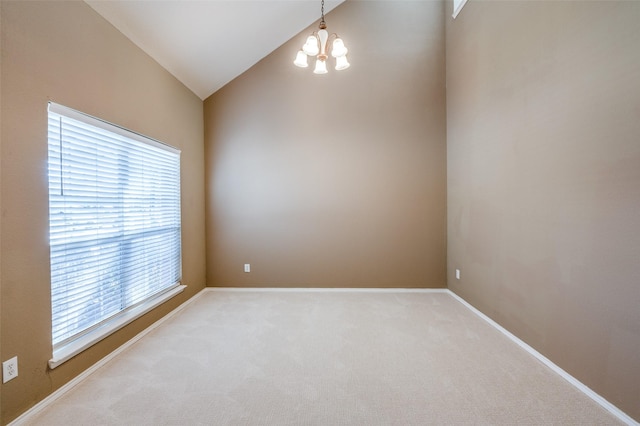 empty room with lofted ceiling, a notable chandelier, light colored carpet, and baseboards