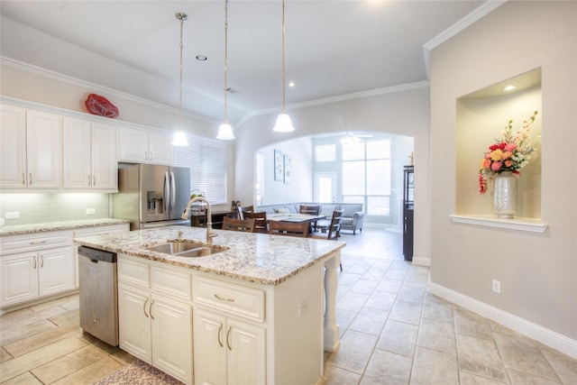 kitchen featuring ornamental molding, a sink, backsplash, arched walkways, and appliances with stainless steel finishes