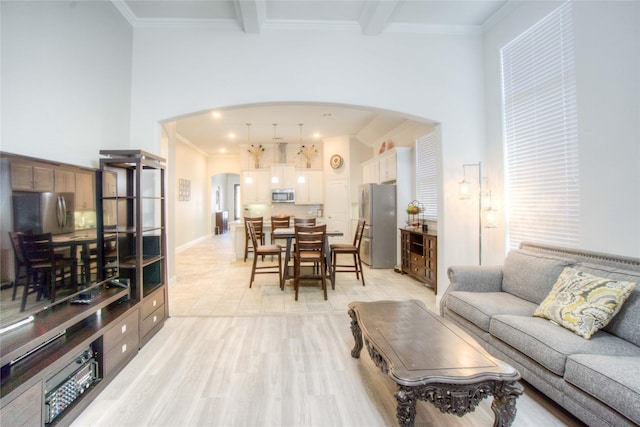 living room with baseboards, light wood-style flooring, arched walkways, ornamental molding, and beamed ceiling