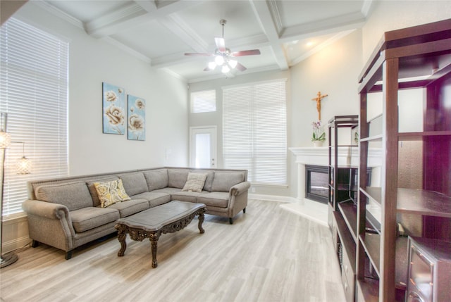 living room with beam ceiling, a glass covered fireplace, and light wood-style floors