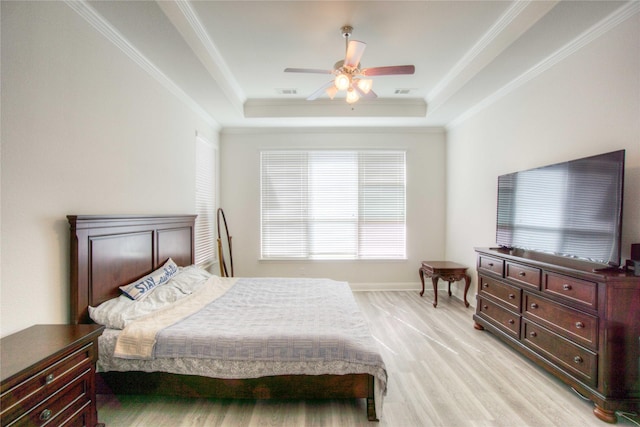 bedroom with baseboards, ceiling fan, ornamental molding, light wood-style flooring, and a raised ceiling