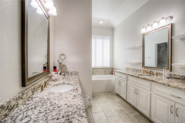 full bathroom featuring a bath, two vanities, and a sink