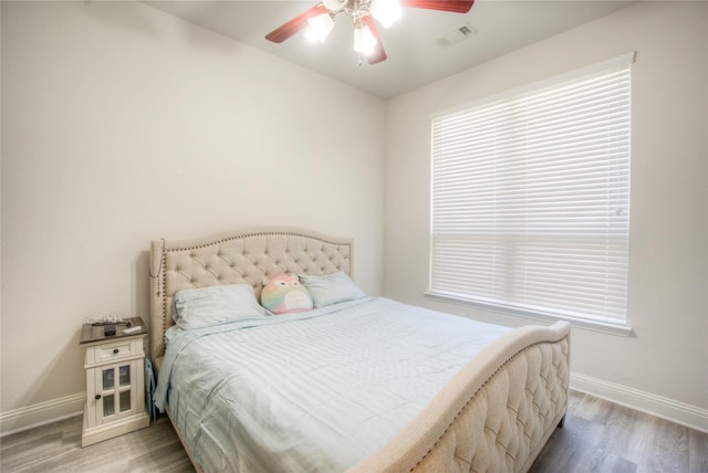 bedroom featuring baseboards, visible vents, light wood finished floors, and ceiling fan