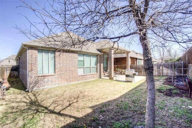 rear view of property featuring a patio, a yard, a fenced backyard, and brick siding