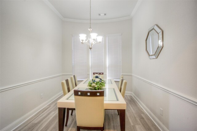 dining room with crown molding, wood finished floors, and a chandelier