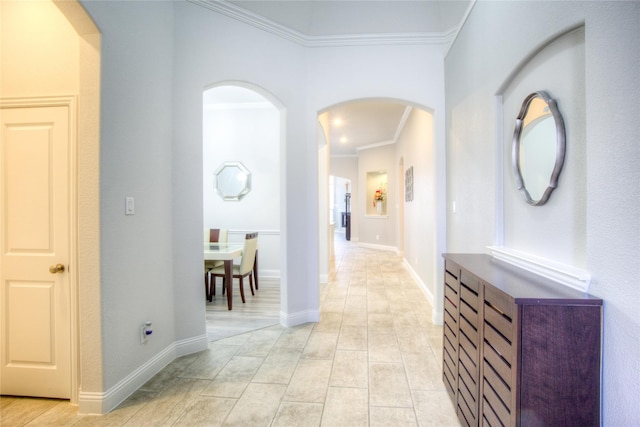 corridor with baseboards, arched walkways, and crown molding